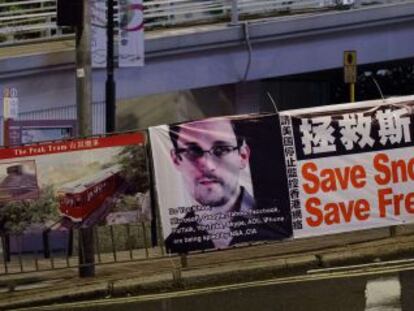 Una mujer espera para cruzar una calle junto a un cartel desplegado en apoyo a Edward Snowden en Hong Kong.