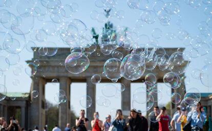 Los turistas fotografían pompas de jabón frente a la Puerta de Brandenburgo, en Berlín.