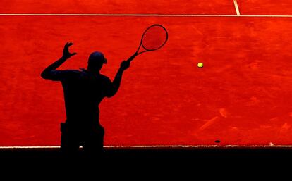 La silueta del jugador norteamericano John Isner se proyecta en la arena de una pista de la Caja Mágica, durante el torneo de tenis Mutua de Madrid.