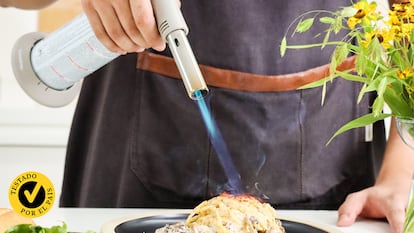 Un cocinero utilizando un soplete sobre un plato de pasta