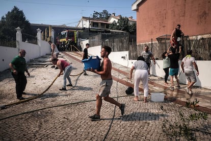 Vecinos de Caneças montan una cadena humana con cubos de agua para intentar apagar las llamas que amenaza sus viviendas.