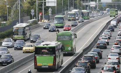 Varios autobuses interurbanos circulan por distintos carriles de la A-6, incluido el Bus-VAO, un día laborable con atascos.