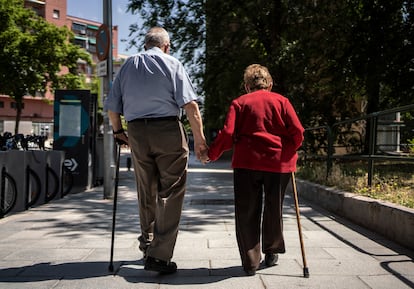 Dos ancianos caminan de la mano por una calle de Madrid.