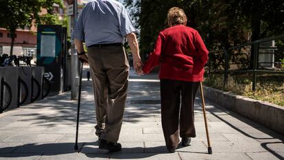 Dos ancianos caminan de la mano por una calle de Madrid.