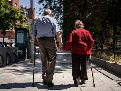 Dos ancianos caminan de la mano por la calle Caramuel, en Madrid.