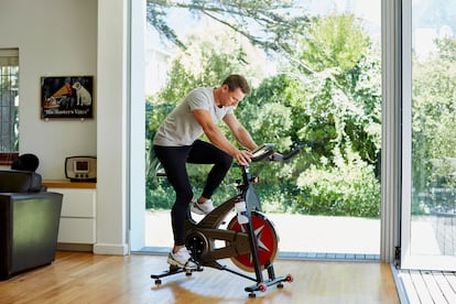 Un hombre hace ejercicio en una bicicleta estática, en el salón de su casa