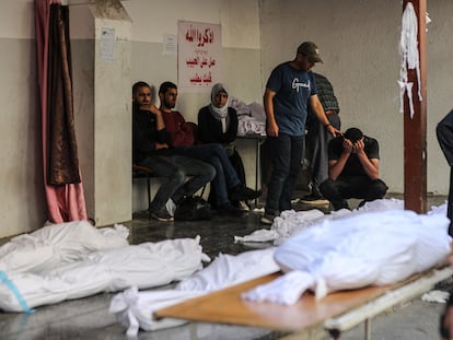 Varios palestinos, ante los cadáveres de víctimas de ataques israelíes en el hospital de Al Ahli en Gaza.