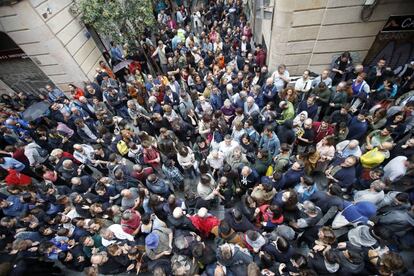 Numerosas personas esperan a las afueras del colegio Cervantes de Barcelona para votar.