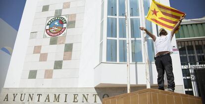 Un operario del Ayuntamiento de Marinnaleda (Sevilla) iza una bandera estelada independentista catalana.