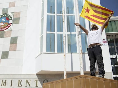 Un operario del Ayuntamiento de Marinnaleda (Sevilla) iza una bandera estelada independentista catalana.