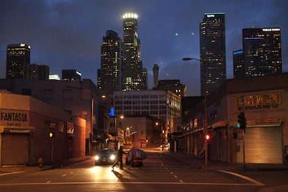 Um morador de rua empurra um carrinho de supermercado com todos os seus pertences em uma rua de Skid Row, a zona mais degradada das periferias de Los Angeles.