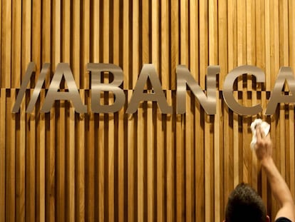 Un operario limpia en una oficina de Santiago el logotipo de Abanca. 