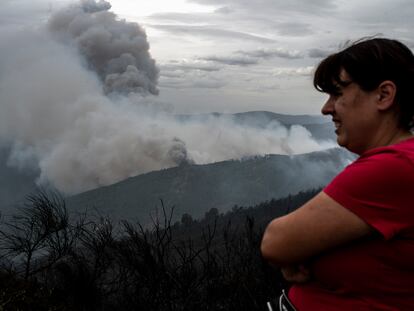 Una vecina de Ribas de Sil (Lugo) observa la columna de humo, este lunes.