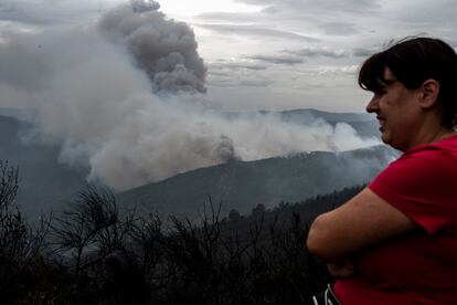 Una vecina de Ribas de Sil (Lugo) observa la columna de humo, este lunes.