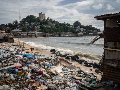 Un señor recoge objetos entre la basura de West Point. Al fondo, la colina que separa el 'slum' del centro de la ciudad.