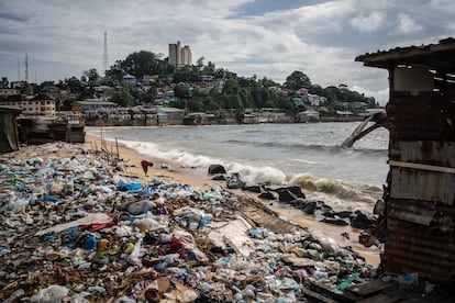 Un señor recoge objetos entre la basura de West Point. Al fondo, la colina que separa el 'slum' del centro de la ciudad.