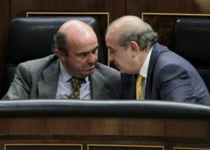 Los ministros de Economía, Luis de Guindos (i) e Interior, Jorge Fernández Díaz, conversan durante la sesión de control al Ejecutivo celebrada hoy en el Congreso de los Diputados.