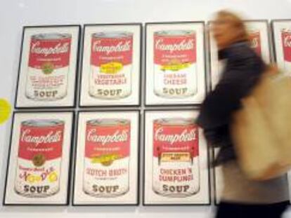 Una mujer camina delante de un trabajo del artista estadounidense Andy Warhol, que muestra las simbólicas latas de sopa Campbell, expuesto en el Museo del Novecento en Milán, Italia. EFE/Archivo