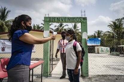 Las familias tendrán que asumir el costo del gel antibacterial y otros artículos de limpieza tras el reinicio de las clases presenciales. En la imagen, Aracely Muñoz, de 35 años y habitante de Canasayab, toma la temperatura de Rubisela Hernandez, alumna de la escuela primaria "Venustiano Carranza".