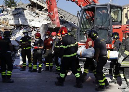 Equipos de rescate transportan un cuerpo de una mujer hallado en una de las casas afectadas por el terremoto, en Amatrice.