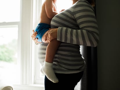 Una embarazada sostiene a un niño en brazos.
