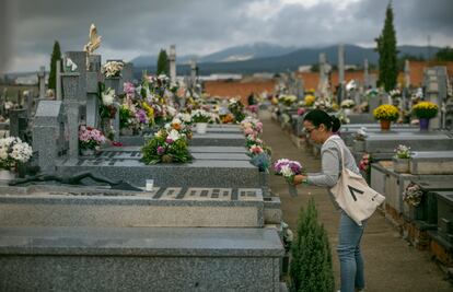 Una mujer deposita flores en una tumba del cementerio de Colmenar Viejo, este martes. La Comunidad de Madrid, a través de sus oficinas y portal oficial de turismo, ha facilitado la visita a diversos cementerios singulares en la región, coincidiendo con la celebración del Día de Todos los Santos. 
