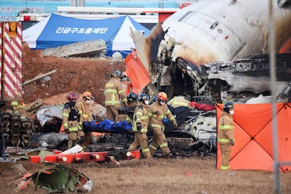 Bomberos trasladan el cadver de un pasajero rescatado entre los restos del avin siniestrado, este domingo en el aeropuerto coreano de Muan.