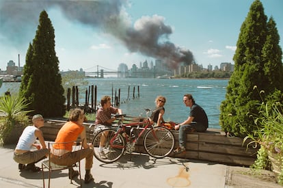 Un grupo de jóvenes se relajan durante su pausa para almorzar en el East River mientras una enorme columna de humo se eleva sobre Manhattan tras el ataque al World Trade Center. Nueva York, 11 de septiembre de 2001. 