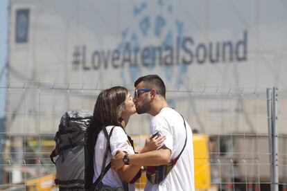 Una pareja se besa frente al cartel con el hashtag del festival #LoveArenalSound, en Burriana, Castellón.