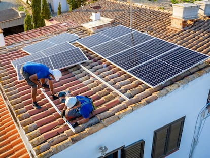 Dos operarios instalan paneles solares en una vivienda.