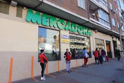 Clientes hacen cola a la entrada de un supermercado respectando la distancia de seguridad.