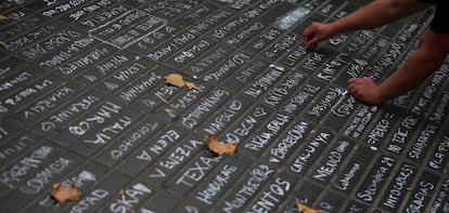 Cientos de turistas apuntan los países a los que pertenecen en el suelo de La Rambla, en solidaridad con los fallecidos en el atentado de Barcelona.