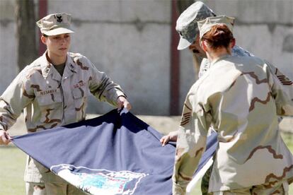 Soldados norteamericanos de la Fuerza Internacional de Asistencia a la Seguridad (ISAF) bajo mando de la OTAN, despliegan una bandera de la coalición durante la ceremonia de traspaso del control.