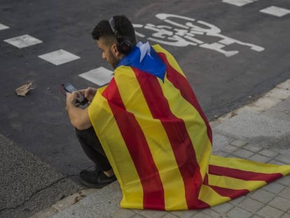 Um jovem sentado com uma bandeira da Catalunha em Barcelona nesta quinta. 