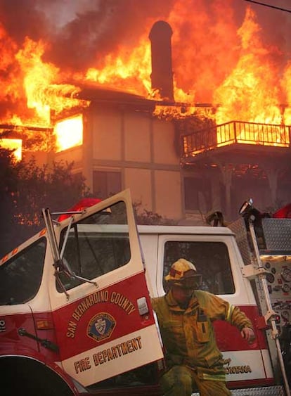 Un bombero del condado de San Bernardino baja del camión ante una casa en llamas.