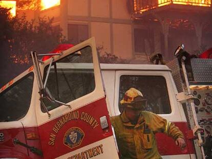 Un bombero del condado de San Bernardino baja del camión ante una casa en llamas.