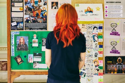 Sara contempla los trabajos de niños de primaria.