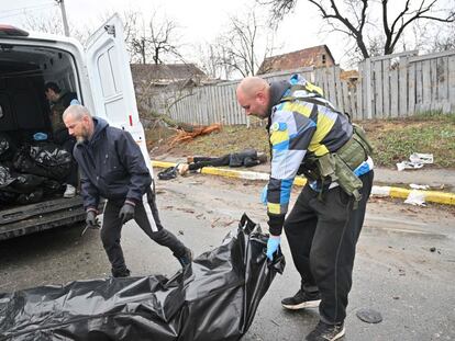 Civiles ucranios trasladan cadáveres, asesinados por las tropas rusas, en Bucha, este domingo.