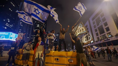 Manifestantes israelíes ondean banderas nacionales encaramados en una barricada, durante la protesta contra el proyecto de reforma judicial, este sábado en Tel Aviv.