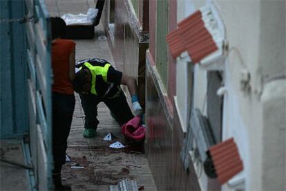 La Policía científica examina pruebas en la puerta de la vivienda de Alzira donde se ha producido el tiroteo.
