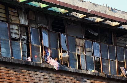 A resident looks out from a window of a building near the apartment block where a deadly fire broke out, in Johannesburg, South Africa, September 1, 2023.