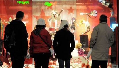 Un grupo de viandantes contempla un escaparate navideño.