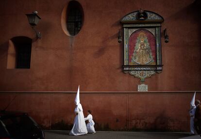 Dos penintes de la hermandad de "San Gonzalo" abandonan la procesión, cancelada por la lluvia en Sevilla.