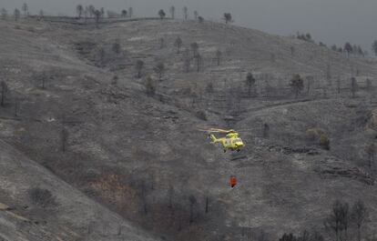 Un helicóptero sobrevuela una zona devastada por las llamas.