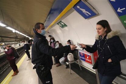 Un agente de policía reparte mascarillas de protección en una estación del metro madrileño.