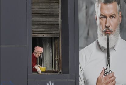 An elderly woman cleans a window next to an advertising poster in Bucharest, Romania, Friday, Dec. 9, 2016. Romanians will vote in parliamentary elections on Dec. 11, a year after a massive anti-corruption drive forced its last prime minister Victor Ponta from power, media moguls were imprisoned and one of the leaders of the second biggest party quit over a graft probe. ()