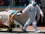 A health worker wearing personal protective equipment (PPE) carries a patient suffering from the coronavirus disease (COVID-19) outside the casualty ward at Guru Teg Bahadur hospital, in New Delhi, India, April 24, 2021. REUTERS/Adnan Abidi     TPX IMAGES OF THE DAY