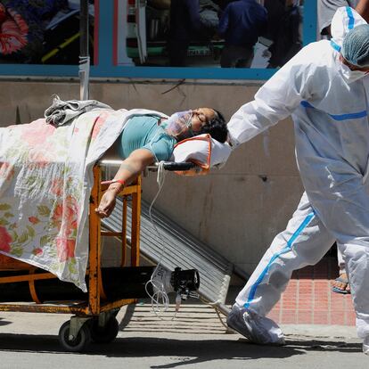 A health worker wearing personal protective equipment (PPE) carries a patient suffering from the coronavirus disease (COVID-19) outside the casualty ward at Guru Teg Bahadur hospital, in New Delhi, India, April 24, 2021. REUTERS/Adnan Abidi     TPX IMAGES OF THE DAY