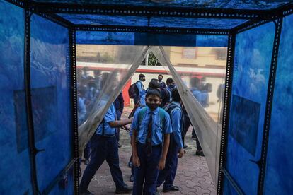 Un grupo de alumnos espera acceder a las instalaciones por un túnel de desinfección después de reanudar las clases físicas en Calcuta (India).