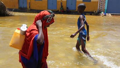 Una mujer y un niño caminan entre el agua tras una inundación.